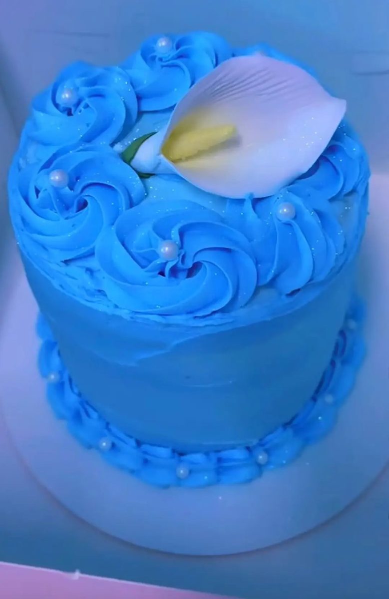 Tall blue buttercream cake covered in piped rosettes and sugar pearls, topped with a white calla lily